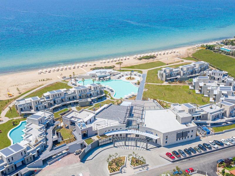 Vista aérea de un gran resort de playa con piscinas, tumbonas y vista al mar.