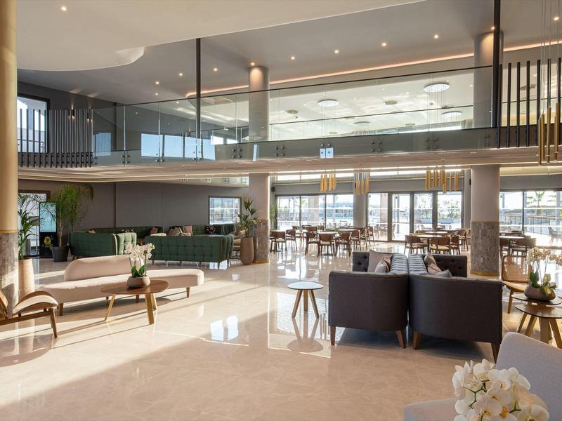 Gran área abierta del vestíbulo del hotel con mobiliario moderno y luz natural.