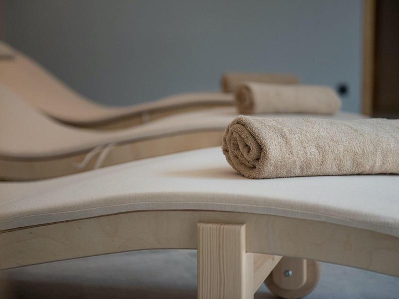 Tres tumbonas blancas con toallas enrolladas en un área interior tranquila.