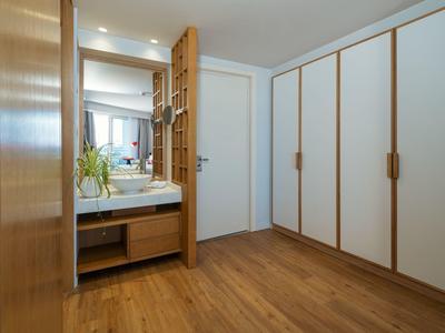 Bright dressing area with wooden floor, white wardrobe, and washbasin with plant.