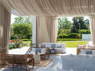 Helles, luftiges Lounge-Set mit Kissen unter einem weißen Baldachin im Garten.