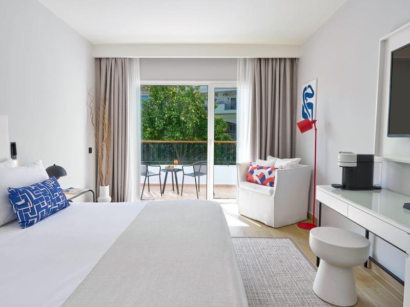 Modern hotel room with double bed, terrace, and garden view.