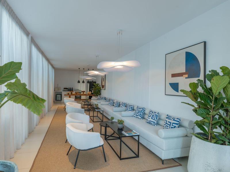 Modern cozy living room with white sofa, armchairs, plants, and abstract wall art.