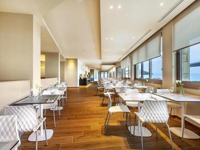 Modern dining room with large windows and wooden floor offering sea views.