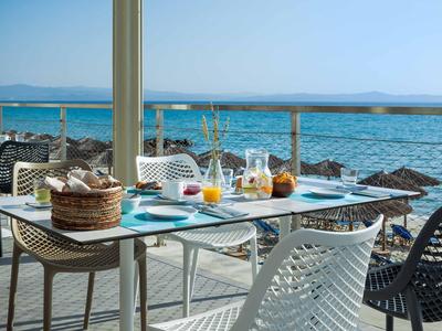 Terrace with set breakfast table overlooking the sea and woven plastic chairs