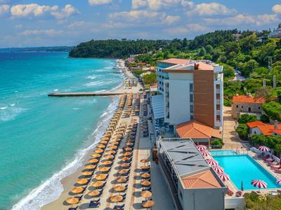 Beach hotel with pool, sun umbrellas, and sea view along the coastline.
