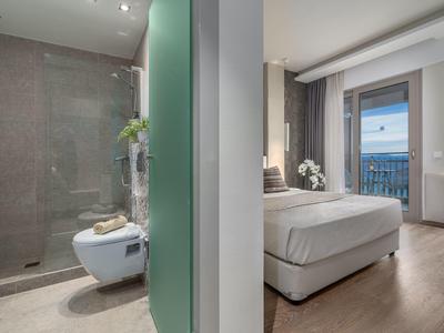 Modern hotel room with balcony and adjoining bathroom with shower.