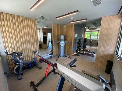 Moderner Fitnessraum mit Cardiogeräten, Hanteln und Spiegeln in einem Hotel oder Fitnessstudio.