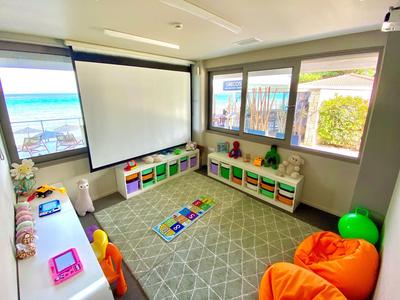 Heller Kinderspielraum mit bunten Sitzkissen und Fensterblick auf das Meer.