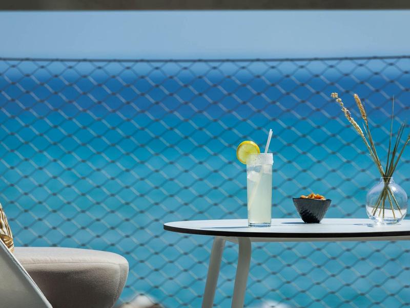 Table with drink and vase by fence overlooking the sea.