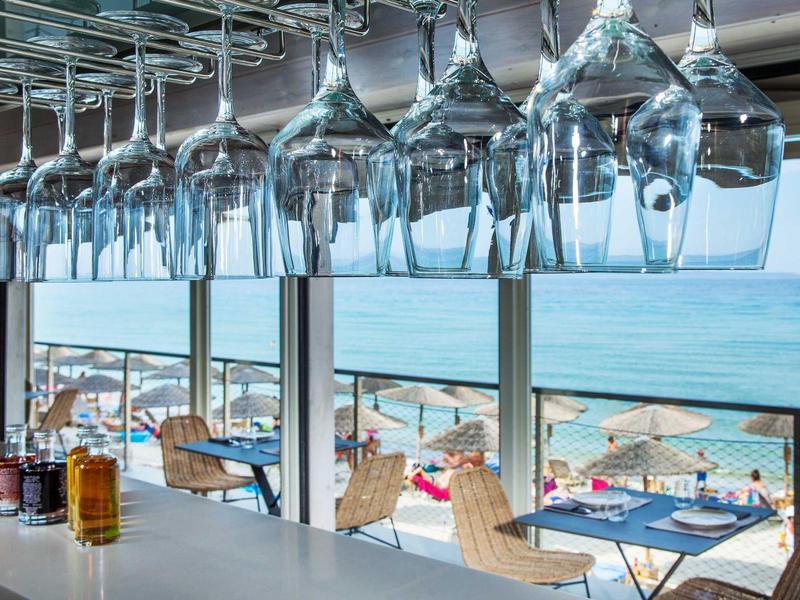 Wine glasses hang above the bar overlooking the terrace and sea.