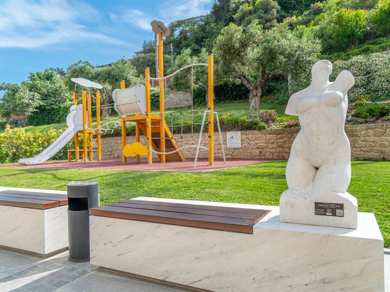 Modern outdoor area with playground and white sculpture next to the swimming pool.