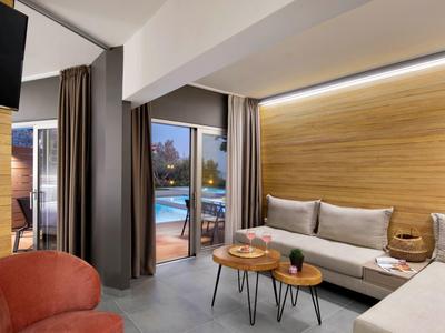 Modernes Wohnzimmer mit grauem Sofa, Holzverkleidung, runden Tischen und Terrassentür zum Außenbereich.