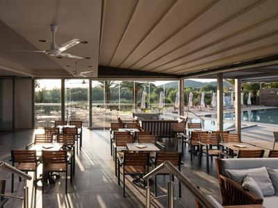Terrasse mit Holzmöbeln und Blick auf den Swimmingpool in einem Hotel.