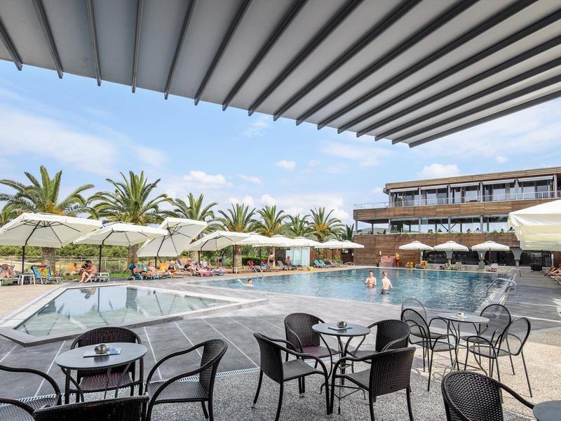 Moderner Außenpoolbereich mit Liegen, Sonnenschirmen und Sitzgruppen unter Überdachung.