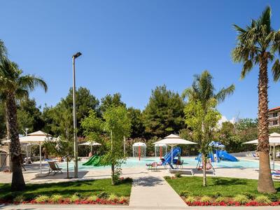Leisure area with swimming pool, slides, and palm trees under clear blue sky.