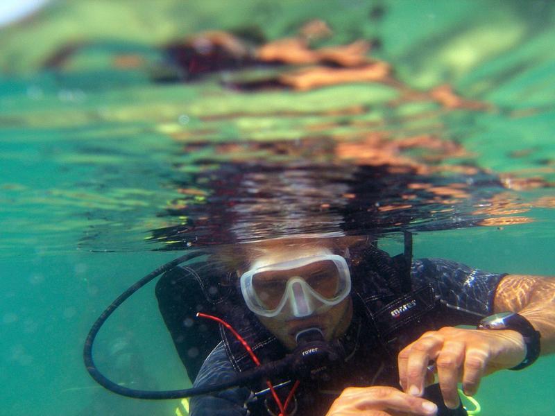 Diver wearing mask and snorkel gear underwater in clear sea.