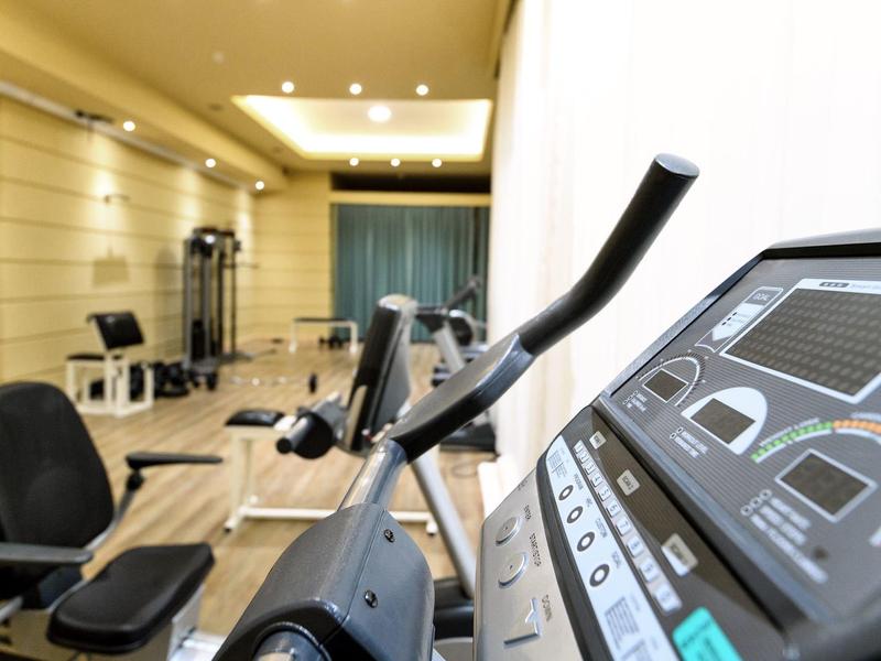 Modern gym room with exercise equipment and bright, warm lighting