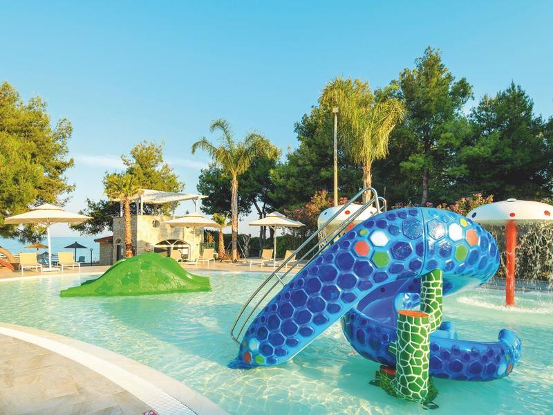 Colorful water playground with slide and spraying water jets in an outdoor hotel pool