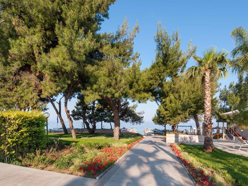 Paths between trees and lounge chairs lead to a view of the sea.