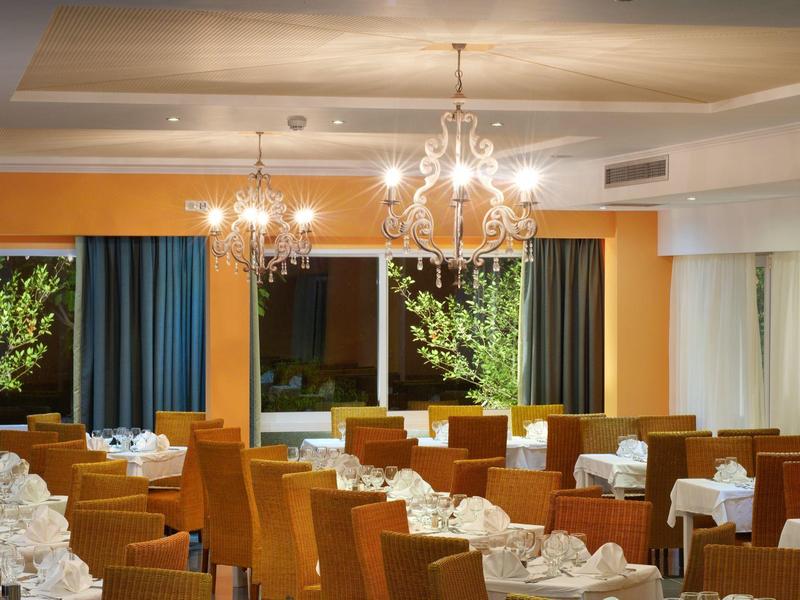 Elegant restaurant with orange chairs and chandeliers in a hotel.