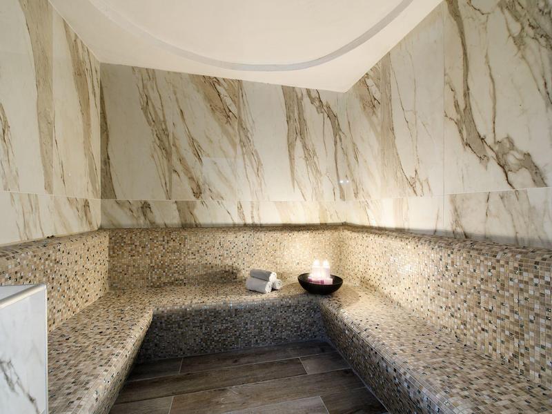Modern sauna room with mosaic tiles and marble finish on the walls.