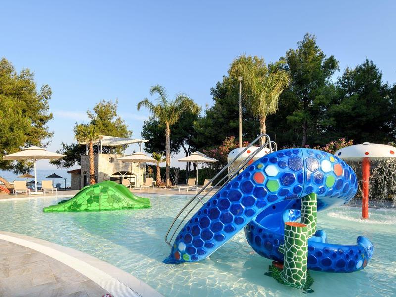 Colorful water park with blue and green slides outdoors under clear sky