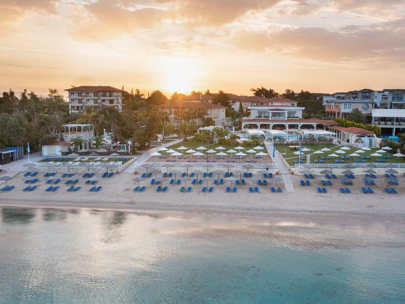 Beach resort with sun loungers and calm sea at sunset.