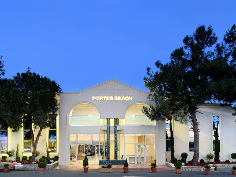 Entrance of a hotel with white facade, illuminated at night under clear sky.