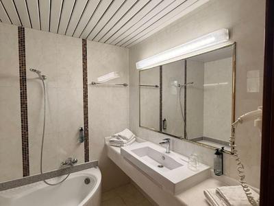 Moderne badkamer met hoekbad, grote spiegel en twee wastafels in neutrale tinten.