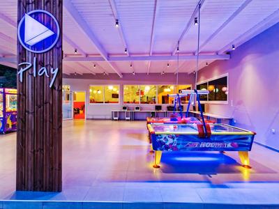 Moderní arkádová místnost s podsvíceným stolem na air hockey pod fialovým osvětlením.