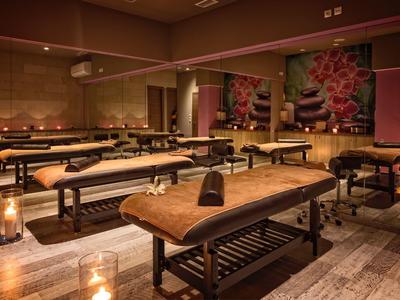 Prostorná spa místnost se dřevěnými masážními stoly a jemným teplým osvětlením.