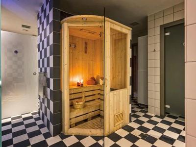 Dřevěná sauna v dlažbě wellness oblasti s černo-bílou šachovnicovou podlahou.