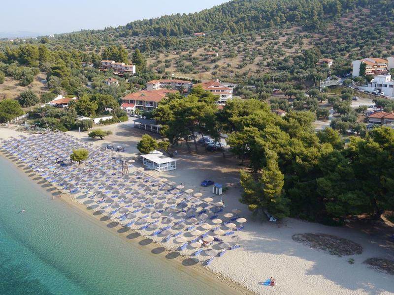 Plážové středisko s řadami slunečníků a lehátek podél písčitého pobřeží u čisté vody.