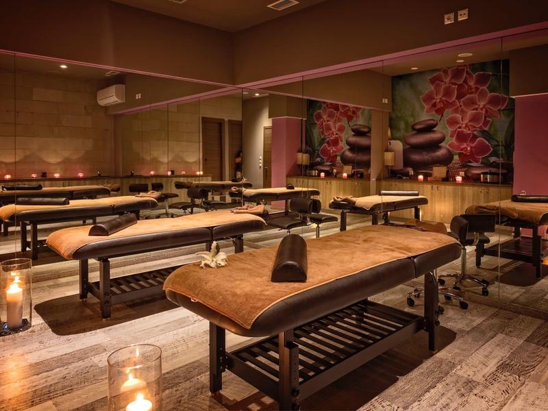 Prostorná spa místnost se dřevěnými masážními stoly a jemným teplým osvětlením.