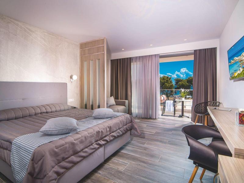 Chambre d'hôtel moderne avec lit double, balcon et vue sur la montagne.