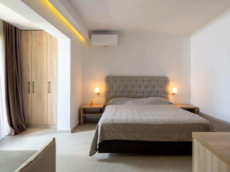 Chambre d'hôtel lumineuse avec lit double, tables de chevet et armoire intégrée.