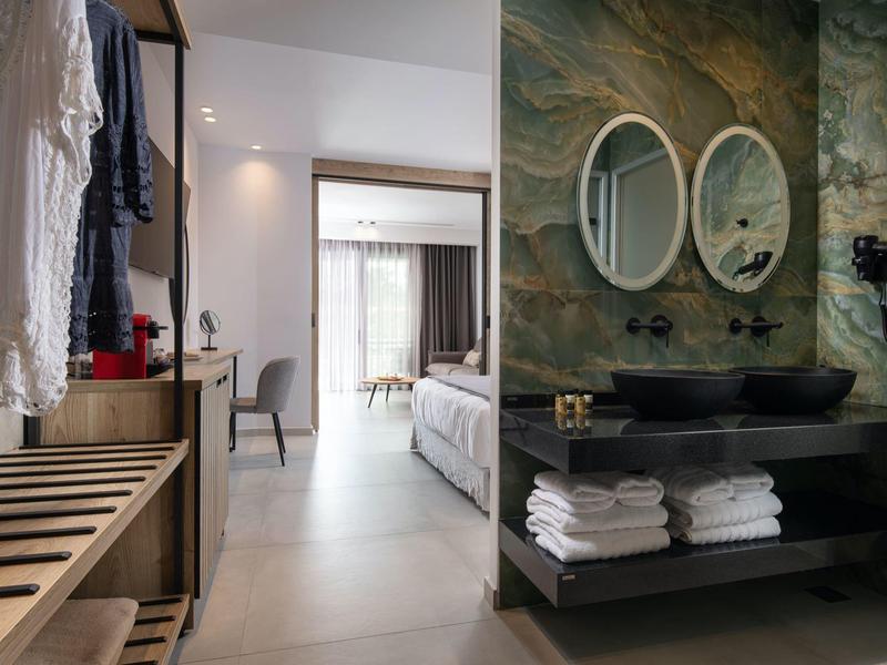 Chambre d'hôtel moderne avec salle de bain, doubles lavabos et accès à la chambre.