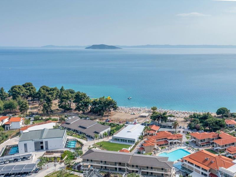 Vue d'une station balnéaire avec plage, mer et île à l'horizon.