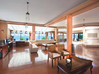 Großer, heller Wohnraum mit Stühlen, Sofas, Tisch und Panoramafenstern mit Meerblick.