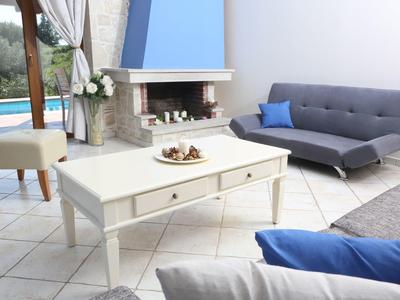 Modernes Wohnzimmer mit grauem Sofa, weißem Couchtisch und Kamin, helle Fliesen und blaue Akzente.