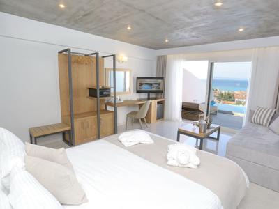 Modernes Schlafzimmer mit großem Bett, Schreibtisch, Sofa und Blick auf Meer und Terrasse.