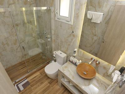 Kleines Bad mit braunem Waschbecken, Toilette, Glasdusche und Holzoptikboden.