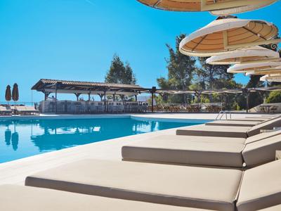 Bequeme Sonnenliegen am Pool mit Sonnenschirmen und freiem Blick auf den klaren Himmel.