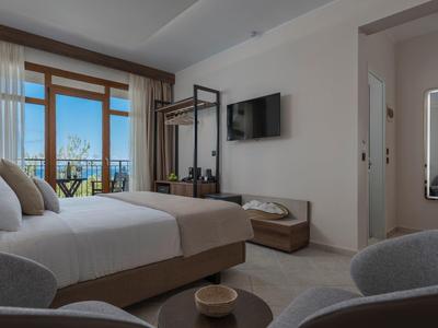 Modernes Schlafzimmer mit Doppelbett, Balkon, grauer Einrichtung und Wand-TV.