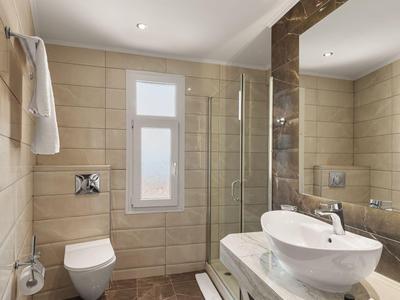 Modern bathroom with shower, sink, and toilet in neutral tones.