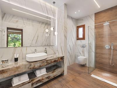Modern hotel bathroom with large mirror, freestanding sink, and wooden elements.