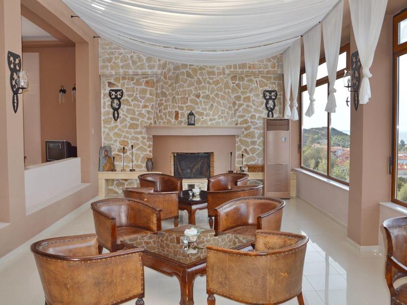 Gemütlicher Raum mit braunen Ledersesseln, Steinkamin und großen Fenstern mit Bergblick.