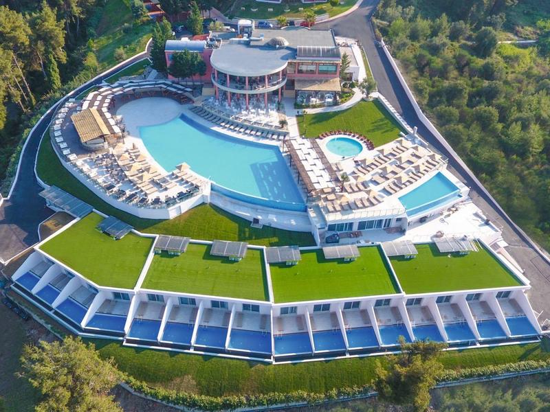 Luxushotel mit großem Pool, Sonnenterrassen und modernen Gebäuden, umgeben von dichtem Wald.