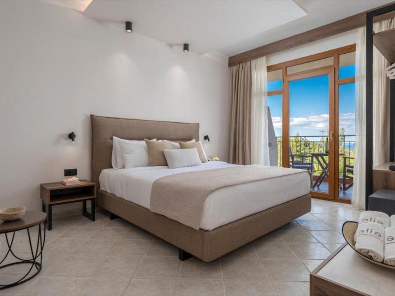 Modernes Hotelzimmer mit großem Bett, Kleiderschrank, Balkon und Blick auf das Meer.